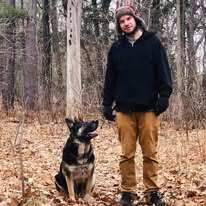 A loved one standing in the woods with a dog
