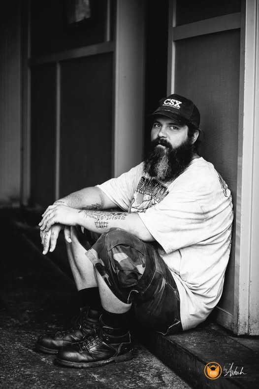 A black and white portrait of a loved one seated by a doorway