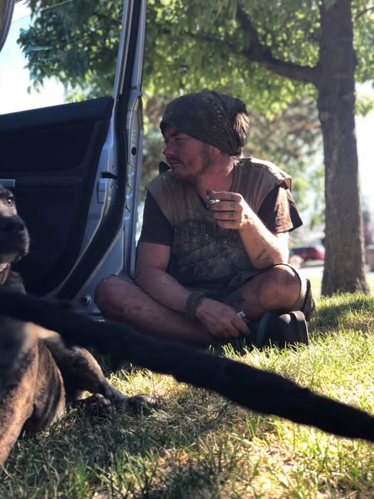 A loved one sitting outside beside a vehicle and dogs
