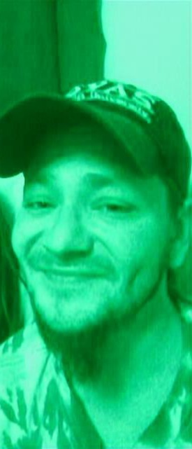 A green-tinted close-up portrait of a loved one smiling in a cap