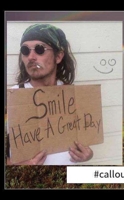A loved one wearing round sunglasses and holding a Smile Have A Great Day sign